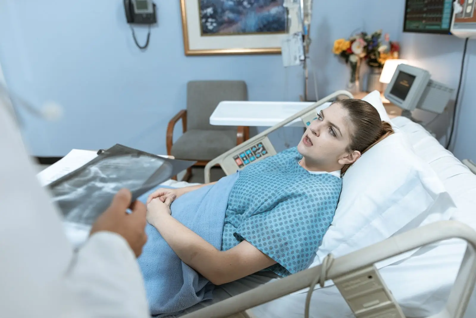 A clinician at a patient's bedside in a hospital ward