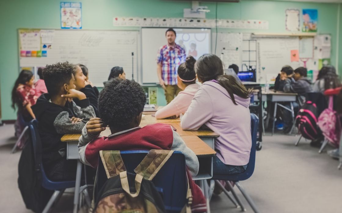 A teacher at the front of a school classroom with students at their desks